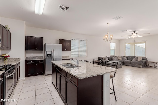 kitchen with sink, a breakfast bar, a kitchen island with sink, appliances with stainless steel finishes, and dark brown cabinetry