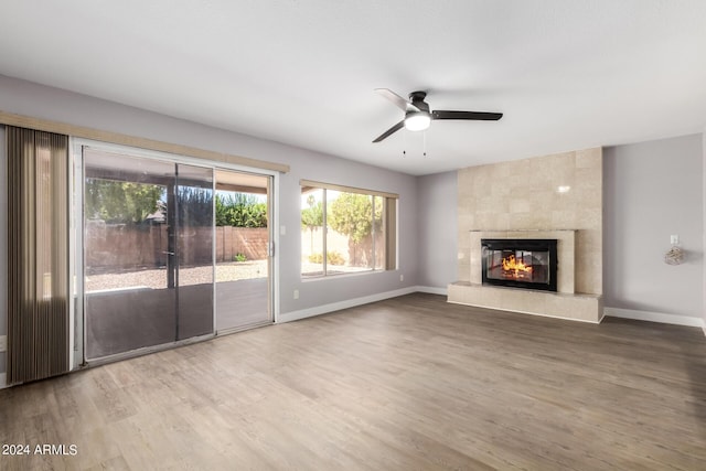 unfurnished living room with ceiling fan, a fireplace, baseboards, and wood finished floors