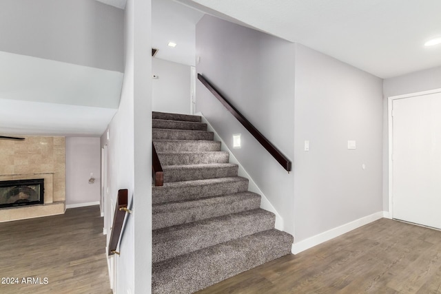 stairway featuring recessed lighting, baseboards, a tiled fireplace, and wood finished floors