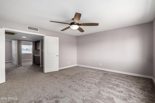 carpeted empty room with baseboards, visible vents, and ceiling fan