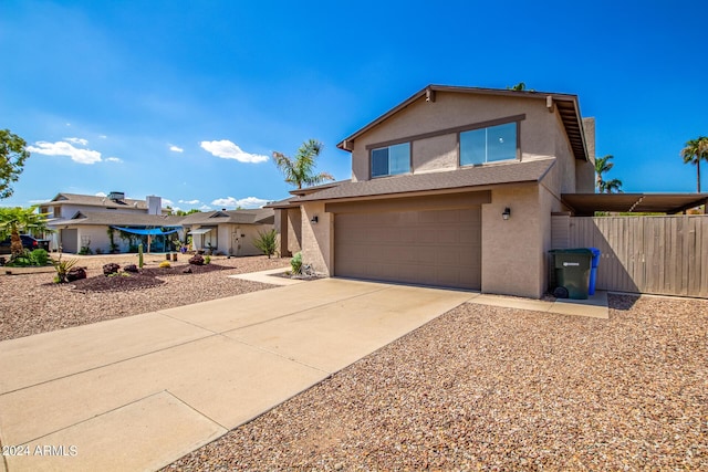 view of front of property featuring driveway, an attached garage, fence, and stucco siding