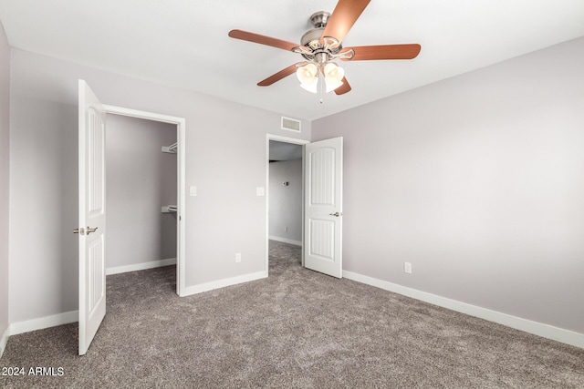 unfurnished bedroom with visible vents, baseboards, ceiling fan, a walk in closet, and carpet floors