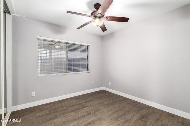 unfurnished room with dark wood-type flooring, a ceiling fan, and baseboards