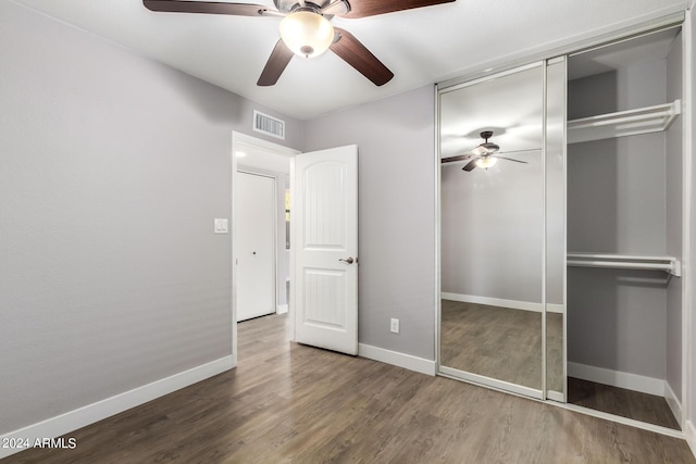 unfurnished bedroom featuring a closet, visible vents, baseboards, and wood finished floors