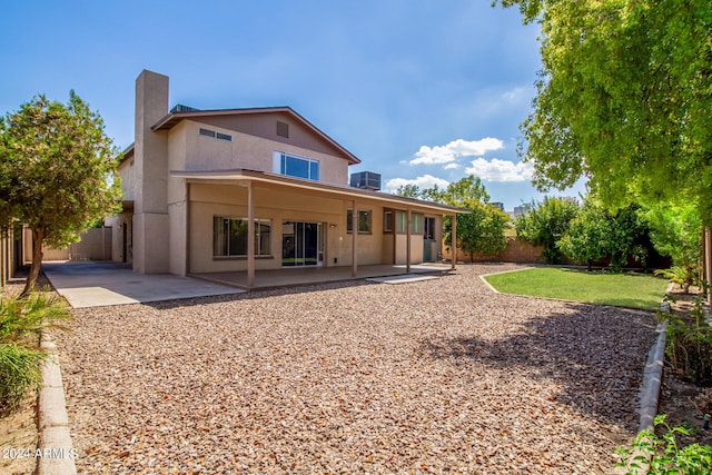 rear view of house with stucco siding, a fenced backyard, and a patio