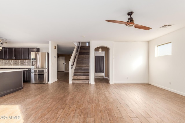18359 W Eva St, Waddell, AZ 85355 - unfurnished living room featuring ceiling fan, stairway, light wood-style floors, baseboards, and arched walkways
