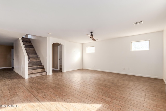 18359 W Eva St, Waddell, AZ 85355 - empty room with arched walkways, ceiling fan, stairs, light wood-style flooring, and baseboards