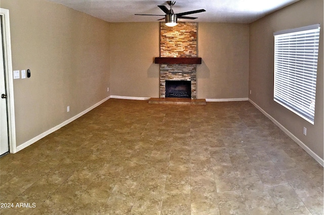 unfurnished living room with ceiling fan, a fireplace, and baseboards