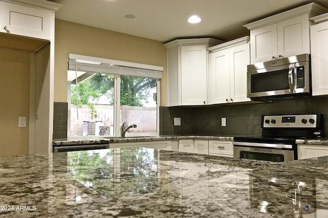 kitchen featuring decorative backsplash, appliances with stainless steel finishes, white cabinets, and a sink