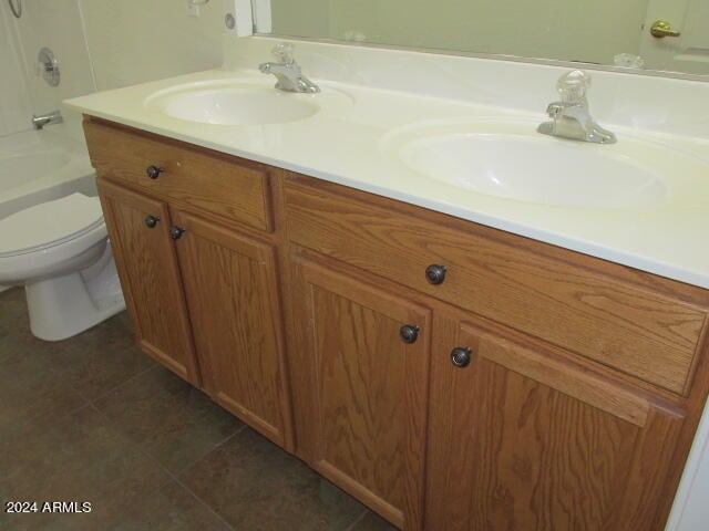 full bathroom with shower / tub combination, double sink vanity, toilet, and tile patterned floors