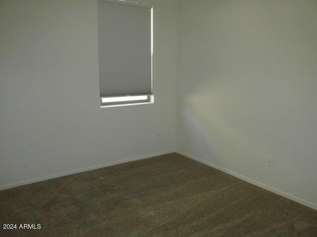 empty room with baseboards and dark carpet