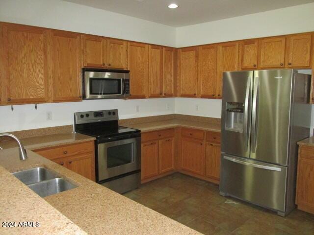 kitchen with a sink, stainless steel appliances, recessed lighting, and brown cabinets