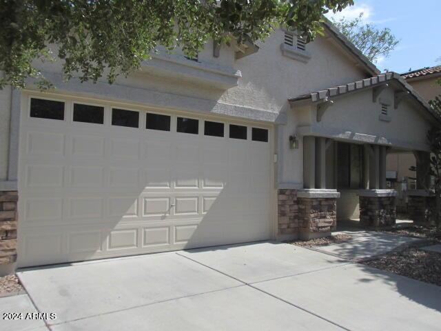exterior space with stone siding, concrete driveway, and stucco siding