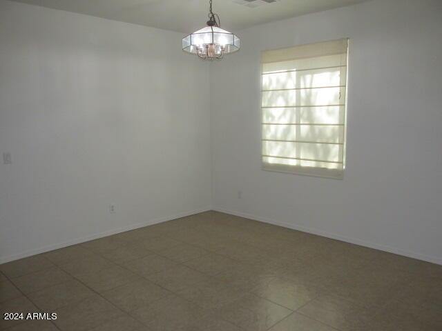 empty room with tile patterned floors, a chandelier, and plenty of natural light