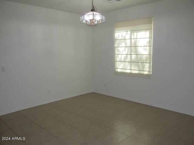 empty room featuring baseboards and a notable chandelier