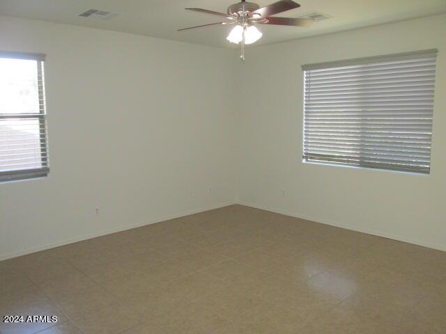 spare room with baseboards, visible vents, and a ceiling fan