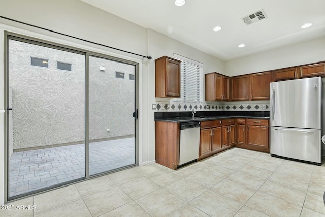 kitchen featuring stainless steel appliances, dark countertops, recessed lighting, visible vents, and tasteful backsplash