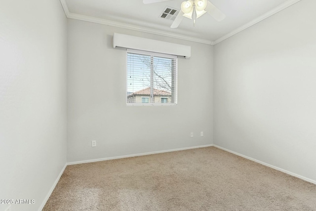 carpeted spare room with baseboards, ceiling fan, visible vents, and crown molding