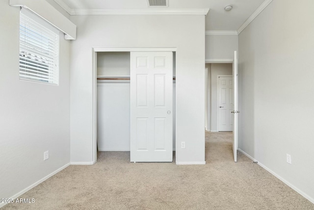 unfurnished bedroom with ornamental molding, a closet, carpet, and baseboards