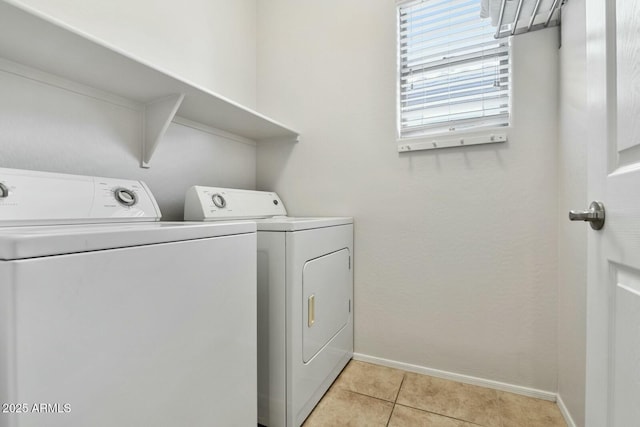 laundry area with laundry area, light tile patterned floors, baseboards, and washing machine and clothes dryer