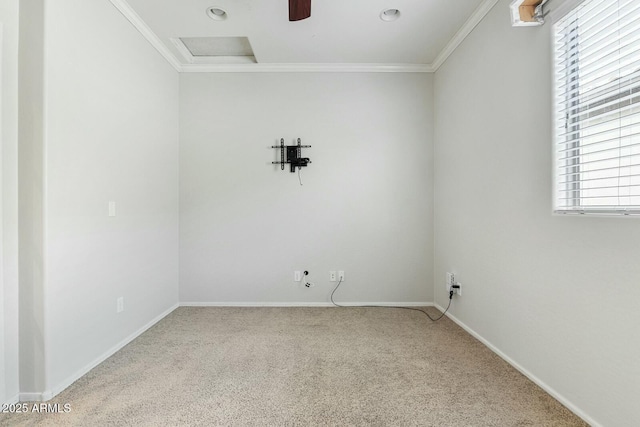 carpeted empty room featuring attic access, baseboards, and crown molding