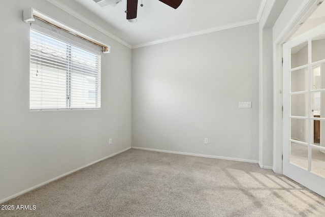 carpeted spare room with baseboards, ornamental molding, and a ceiling fan