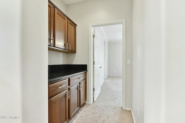 hallway featuring light colored carpet and baseboards