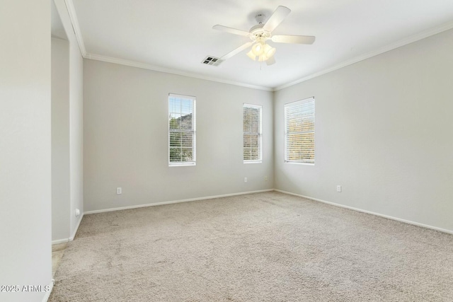 carpeted spare room with baseboards, visible vents, a ceiling fan, and ornamental molding