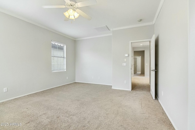 spare room with ornamental molding, light colored carpet, baseboards, and a ceiling fan