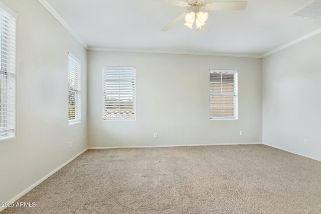 spare room featuring carpet floors, visible vents, ornamental molding, ceiling fan, and baseboards