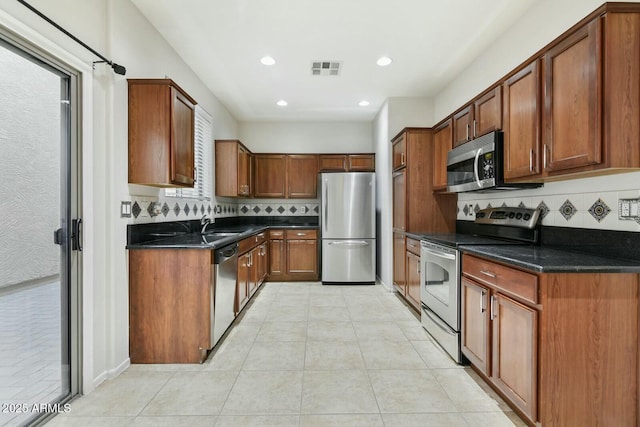 kitchen featuring light tile patterned floors, stainless steel appliances, visible vents, and decorative backsplash