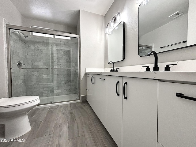 bathroom featuring vanity, toilet, and a shower with door