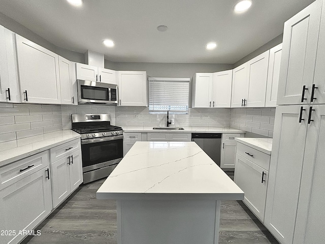 kitchen with appliances with stainless steel finishes, sink, a kitchen island, and white cabinets