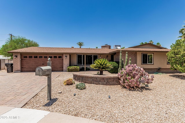 8620 E Sells Dr, Scottsdale, AZ 85251 - ranch-style home featuring an attached garage, brick siding, decorative driveway, and a chimney