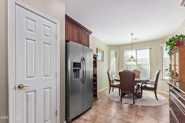 kitchen with light tile patterned flooring, stainless steel fridge with ice dispenser, and decorative light fixtures