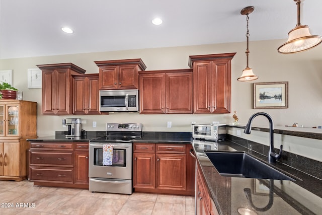 kitchen with appliances with stainless steel finishes, sink, light tile patterned flooring, decorative light fixtures, and dark stone counters