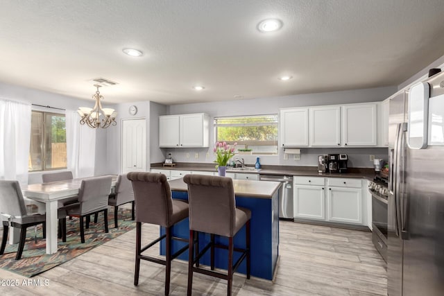 4034 E Mine Shaft Rd, San Tan Valley, AZ 85143 - kitchen featuring appliances with stainless steel finishes, a chandelier, white cabinetry, a breakfast bar area, and a kitchen island