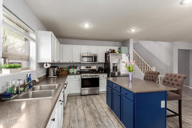 4034 E Mine Shaft Rd, San Tan Valley, AZ 85143 - kitchen with appliances with stainless steel finishes, a sink, blue cabinetry, a kitchen bar, and white cabinetry