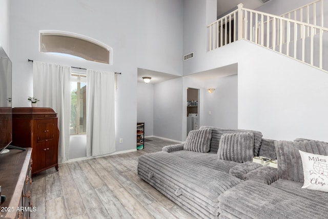 4034 E Mine Shaft Rd, San Tan Valley, AZ 85143 - living room featuring wood finished floors, a towering ceiling, washer and clothes dryer, and baseboards