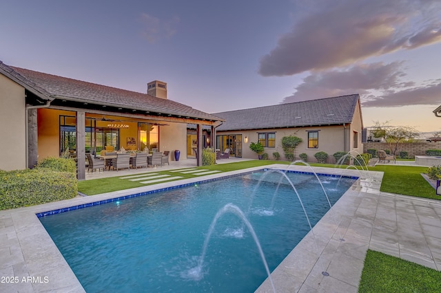 pool at dusk featuring a patio area and pool water feature