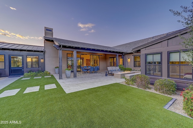 back house at dusk with a patio area, an outdoor living space, and a yard