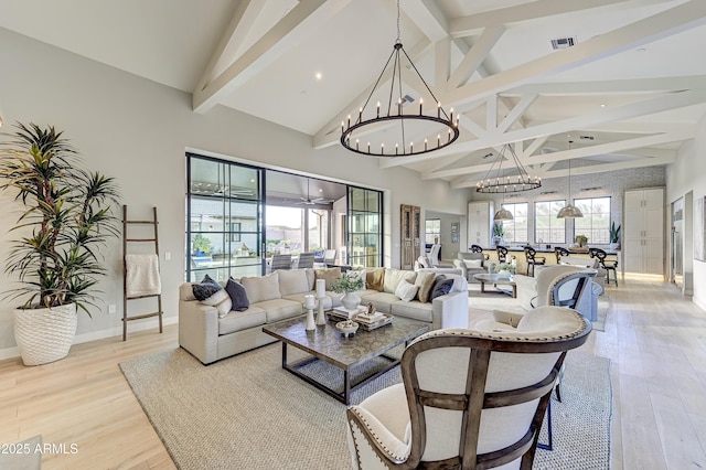 living room with lofted ceiling with beams, light hardwood / wood-style floors, and a chandelier