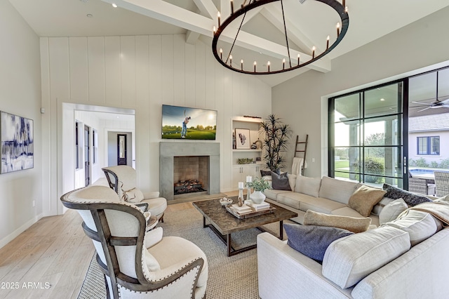 living room with ceiling fan with notable chandelier, beam ceiling, high vaulted ceiling, and light hardwood / wood-style flooring