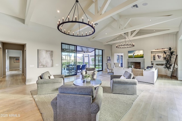 living room with beam ceiling, light wood-type flooring, high vaulted ceiling, and a notable chandelier