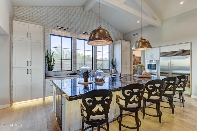 kitchen with stainless steel appliances, light hardwood / wood-style flooring, a center island, white cabinetry, and hanging light fixtures