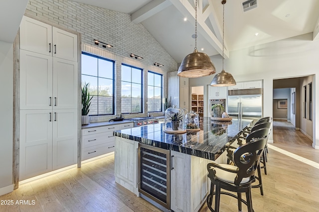 kitchen featuring a center island, beam ceiling, white cabinetry, stainless steel appliances, and beverage cooler