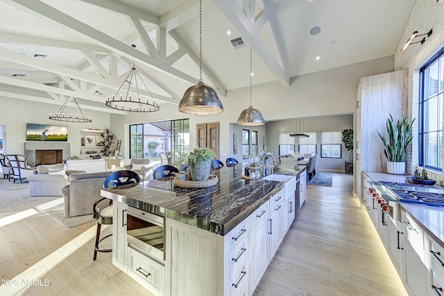 kitchen with beamed ceiling, a large island, pendant lighting, and white cabinetry