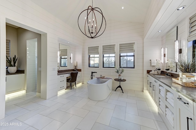 bathroom featuring tile patterned flooring, a bath, a notable chandelier, vaulted ceiling, and vanity