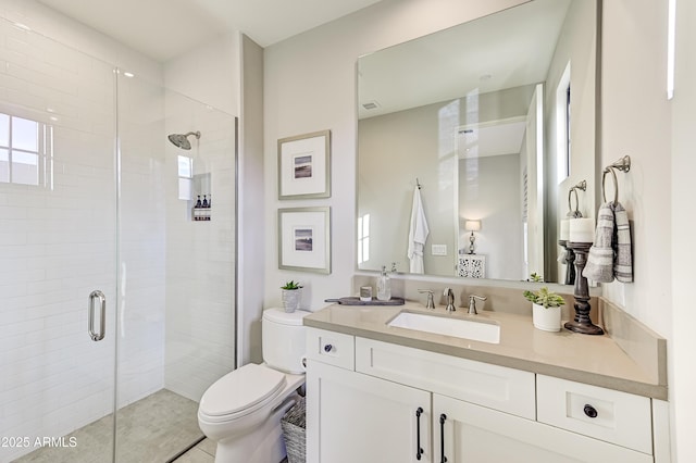 bathroom with tile patterned flooring, vanity, a shower with shower door, and toilet