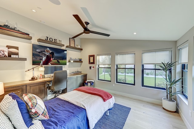 bedroom featuring ceiling fan, light wood-type flooring, built in desk, and vaulted ceiling